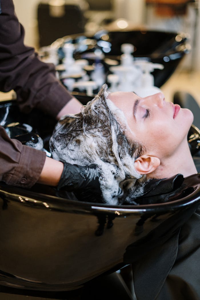Professional hair stylist washing womans hair in a modern salon setting.